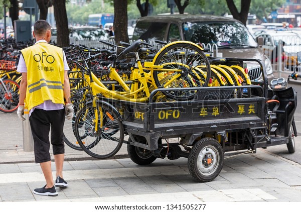BEIJING, CHINA- JULY 23, 2017: An\
operator is seen next to a truck loaded with ofo bicycles at city\
downtown. Ofo is a bike-sharing company founded in\
2014