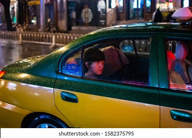 Beijing / China - July 27, 2016: Passenger Taking A Ride On A Beijing City Taxi On A Rainy Night, Dongzhimen Area, Beijing