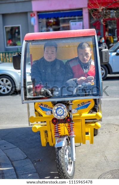 BEIJING, CHINA -\
MARCH 10, 2016: People are driving through the streets with\
bicycles, scooters and cars.With motorcycles transporting people,\
goods, building materials and much\
more.