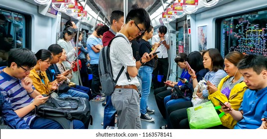 Beijing city, China - May 19, 2018: Chinese people looking at their mobile phones inside a subway train