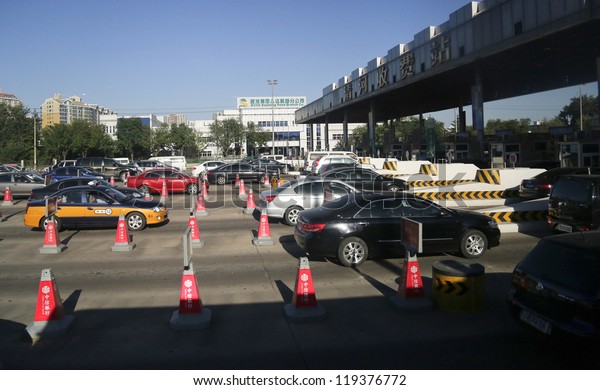 BEIJING - OCTOBER 13: Vehicles line up at the toll\
both of a highway on October 13, 2012 in Beijing, China. Beijing, a\
city of 22 million people has 5 million cars and 2,000 cars are\
added each month.
