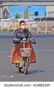 BEIJING-APRIL 28, 2016. Man With 3M Mouth Cap On E-bike. Despite Some Improvements In Worst Areas, Nearly 300 Chinese Cities Failed To Meet The National Air Quality Standards In 2015, Greenpeace Said.