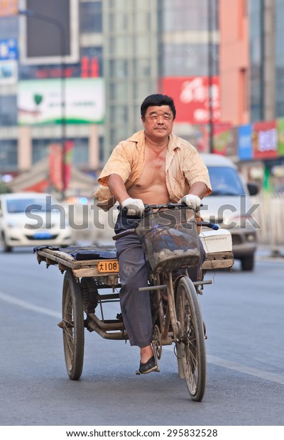 BEIJING-JULY 10, 2015. Man on rusty three wheeled\
freight bike. Although municipal governments try to ban them out\
this transportation mode is still convenient in dense, congested\
Chinese cities. 