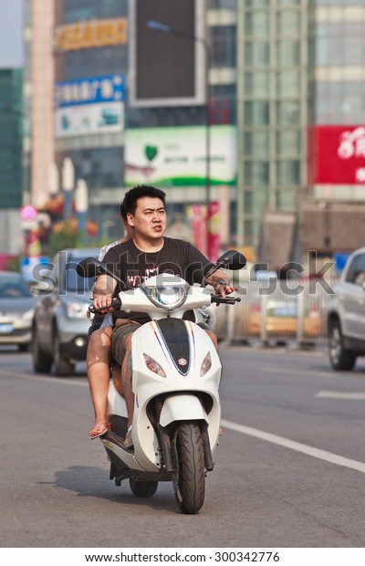 BEIJING-JULY 24, 2015. Couple on electric\
scooter. In a decade, e-bikes in China climbed from near zero to\
150 million (2015), largest adoption of alternative fuel vehicle in\
history of\
motorization.
