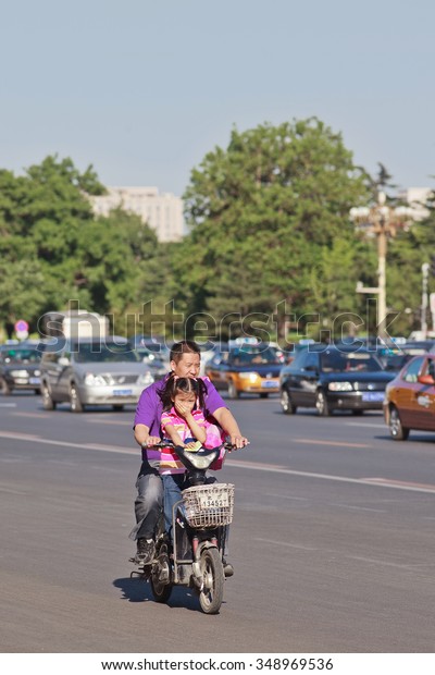 BEIJING-MAY 29, 2013. Father and daughter\
on e-bike. In a decade, e-bikes in China climbed from near zero to\
over 150 million, largest adoption of alternative fuel vehicle in\
history of\
motorization.