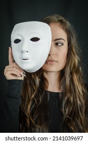 Being Authentic And True Concept -  Portrait Of A Beautiful Young Woman With Long Hair Taking Off Her Mask And Looking To The Side