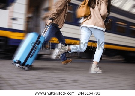Being late. Couple with suitcase running after train on station, closeup. Motion blur effect