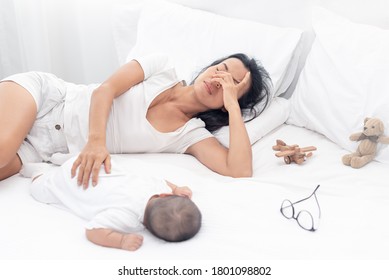 Being Mom Is So Exhausted.  Tired Mother Laid In Bed With Newborn Baby At Night. Authentic Real Life Exhausted Parent Taking Rest With Newborn Child.