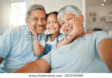 Being part of a family means smiling for photos. Shot of grandparents bonding with their granddaughter on a sofa at home.