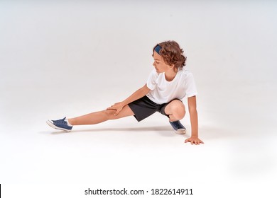 Being physically active. Full length of caucasian teenage boy in sportswear stretching legs, warming up before training isolated over grey background in studio - Shutterstock ID 1822614911