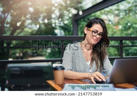 Being productive outside of the office. Cropped shot of an attractive young businesswoman working on her laptop while sitting outdoors at a cafe.