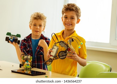 Being proud. Happy positive smart boy feeling proud while showing his robot to you