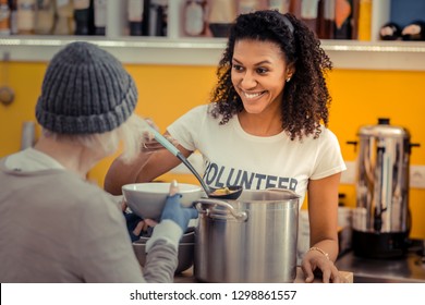 Als Freiwilliger. Nette freundliche Frau lächelend, während sie ihren Job als Freiwillige genießt
