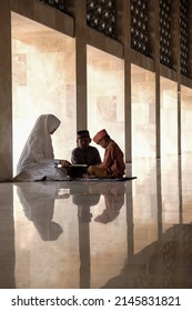 Bekasi, Indonesia. April 2022. Asian boys muslim learning to read the Holy Quran, Alquran with a Muslim teacher or ustadzah. Sunlight creates a reflection effect. Focus selection.