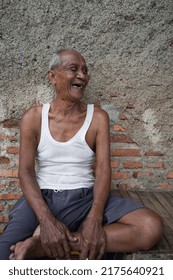 Bekasi, Indonesia - January 3, 2021 : Photograph Background Of Old Grandpa Relaxing Sitting Smiling On The Bench In The Backyard Enjoying The Sunny Morning Weather