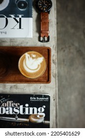 Bekasi, Indonesia - September 20th 2022. Top Angle View Of A Glass Of Hot Cappuccino Coffee With Latte Art On Wooden Pallet And Some Properties On Concrete Bench Inside Cafe. Piccolo Coffee Brewing