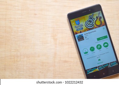 BEKASI, WEST JAVA, INDONESIA. FEBRUARY 11, 2018. Install Application Game Guitar Hero On Your Smartphone With Wood Background