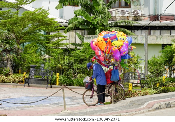 Bekasi, West Java /\
Indonesia - March 26 2019: View of the city public areas by the\
river with artistic facilities and colorful balloon seller captured\
in the morning.