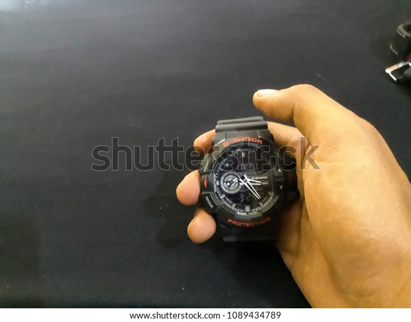 BEKASI, WEST JAVA,\
INDONESIA. MAY 13, 2018 : Man holding beautiful wristwatch on black\
background, focus on hand. Time change concept - Place For Your\
Design, Text