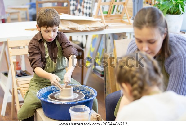 Belarus, the city of Gomel, January 14, 2021.\
Creative workshop. The potter teaches children to sculpt with clay\
using a potter\'s\
wheel.