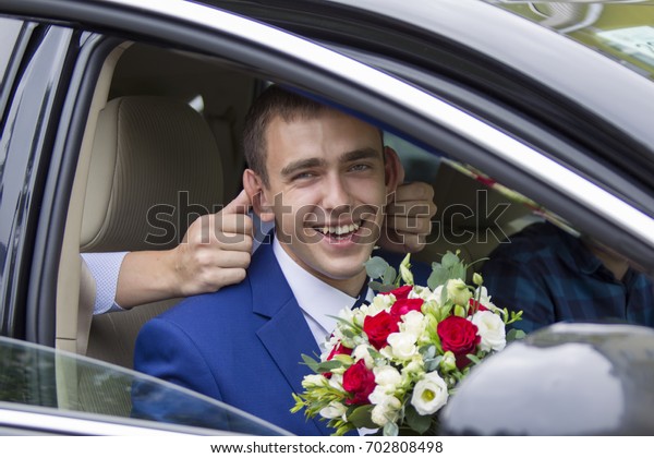 Belarus, the\
city of Gomel.July 15, 2017.Central Wedding House.Cheerful groom\
sitting in the car laughing cheerfully.Merry groom. The bridegroom\
will go to the bride. Groom\
funny