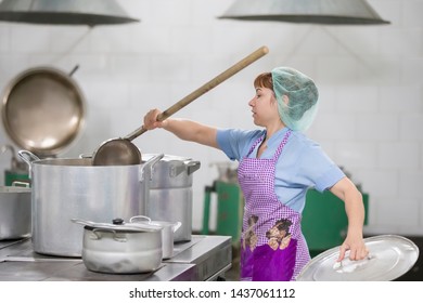 Belarus, Gomel, June 2, 2017.Industrial Kitchen In The Hospital. Cook Prepares Food. Cook With Large Pans And A Ladle. Kitchen Worker With A Ladle. Chef Professional