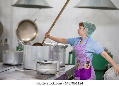 Belarus, Gomel, June 2, 2017.Industrial Kitchen In The Hospital. Cook Prepares Food. Cook With Large Pans And A Ladle. Kitchen Worker With A Ladle. Chef Professional