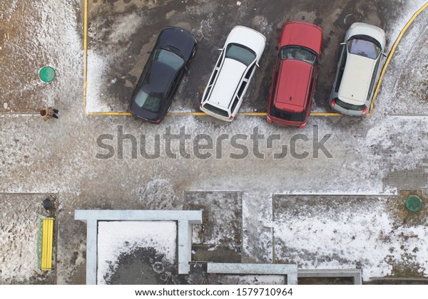 Belarus, Minsk, 2015. Top\
view of a car standing on a snowy asphalt parking lot near an\
apartment building.