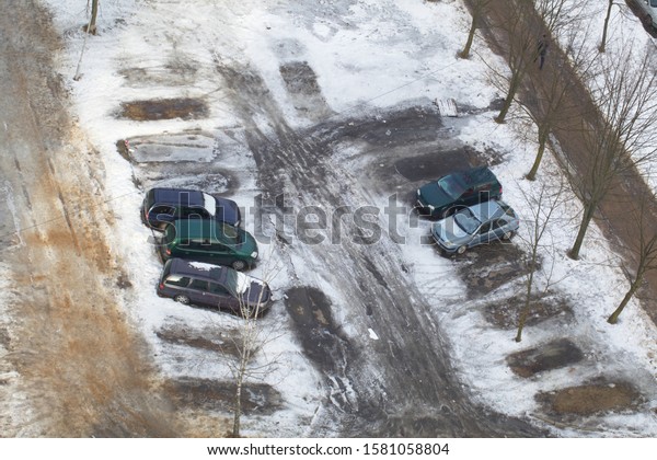 Belarus, Minsk, 2015. Top\
view of a car standing on a snowy asphalt parking lot near an\
apartment building.