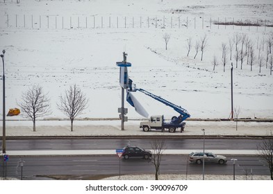 BELARUS, MINSK - MARCH 13/2016: Working On The Lift Basket Repairs Publicity With Billboard.