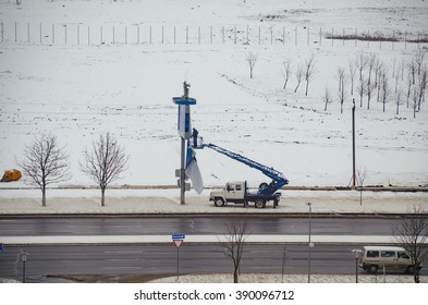 BELARUS, MINSK - MARCH 13/2016: Working On The Lift Basket Repairs Publicity With Billboard.