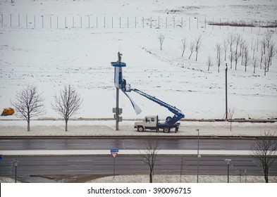 BELARUS, MINSK - MARCH 13/2016: Working On The Lift Basket Repairs Publicity With Billboard.