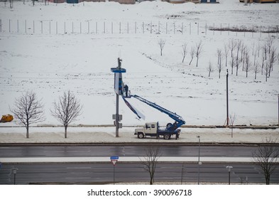 BELARUS, MINSK - MARCH 13/2016: Working On The Lift Basket Repairs Publicity With Billboard.