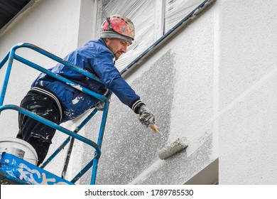 Belarus, Minsk - May 28, 2020: Worker On A Lifting Platform Painting A New Facade Of A House Under Construction At A Construction Site