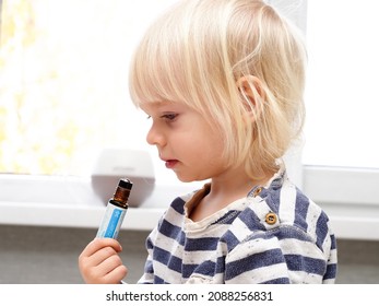 Belarus,minsk,2021. A Little Blond Boy Kid  Child Himself Smells A Rollerball With DoTerra Therapeutic Essential Oil From A Children's Set For Good Health