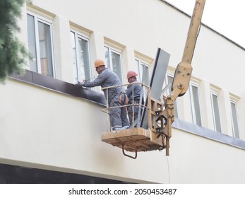 Belarus,minsk,2021.construction Workers Overalls And Paints On A Hydraulic Lift Repair A Window Of A Building Wall