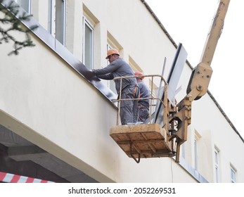 Belarus,minsk,2021.construction Workers Overalls And Paints On A Hydraulic Lift Repair A Window Of A Building Wall