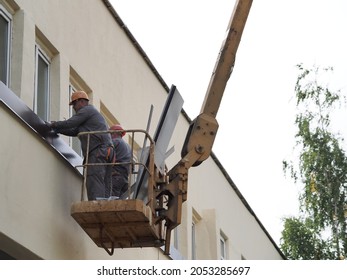 Belarus,minsk,2021.construction Workers Overalls And Paints On A Hydraulic Lift Repair A Window Of A Building Wall