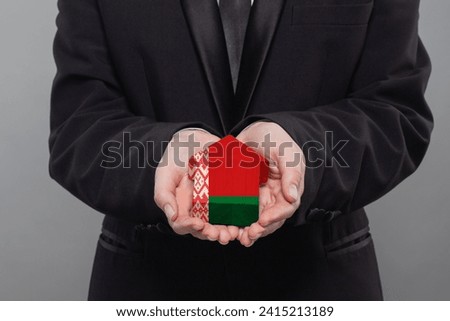 Belarussian person holding wooden house with flag of Belarus Finance, investment, mortgage, loan and credit concept