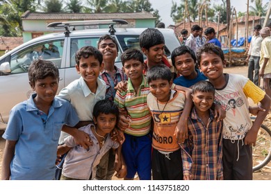 Belathur, Karnataka, India - November 1, 2013: Group of young boys in colorful shirts along street look and smile at camera.