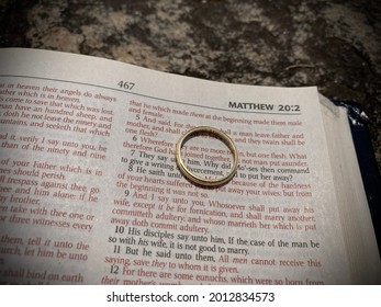 BELCHERTOWN, MASSACHUSETTS, USA - JULY 22, 2021: Close Up Of The Bible Open To Matthew 19 Text With Gold Wedding Band On Page. Difficult Passages About Marriage. Selective Focus, Blur, And Vignette.