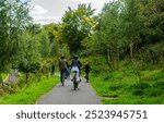 Belfast, County Down, Northern Ireland September 15 2024 - A family on a cycling trip on the towpath beside the River Lagan at Stranmillis, talen from behind