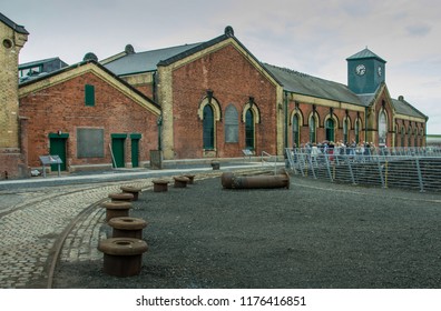 BELFAST, IRELAND - AUGUST 30, 2018: A Tour Group Gathers In Front Of The Titanic Pump House Built During The Edwardian Era That Could Empty The Water From The Enormous Graving Dock In 100 Minutes.