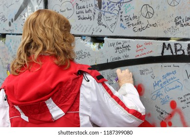 Belfast, Northern Ireland - February 17 2018: A Women Writes On The Wall Of Peace In Belfast Commemorating The Violence That Happened In Northern Ireland. The Wall Is A Tribute To The Troubles.