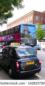 BELFAST, NORTHERN IRELAND - JUNE 02, 2019: A Street Scene With A Typical British Black Cab And A Red Bus In The City Of Belfast