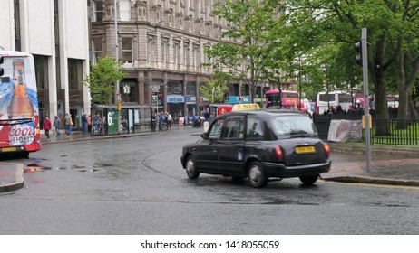 BELFAST, NORTHERN IRELAND – MAY 31, 2019: A Street Scene With A Black Cab And Pedestrians In The City Of Belfast