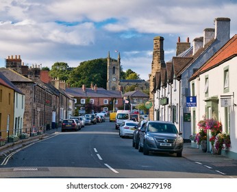 Belford, UK - Sep 11 2021: Sandstone Buildings And The Busy High Street And Church In The Centre Of Belford, An Old, Traditional English Village In Northumberland In The North East Of England, UK.