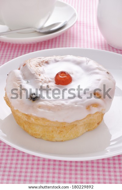 Belgian bun a sweet bun made with sultanas and topped\
with fondant icing 