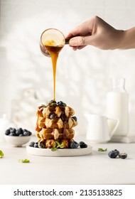 Belgian Handmade Waffles With Caramel And Blueberries On White Table With Pouring Topping.Dessert Photo.