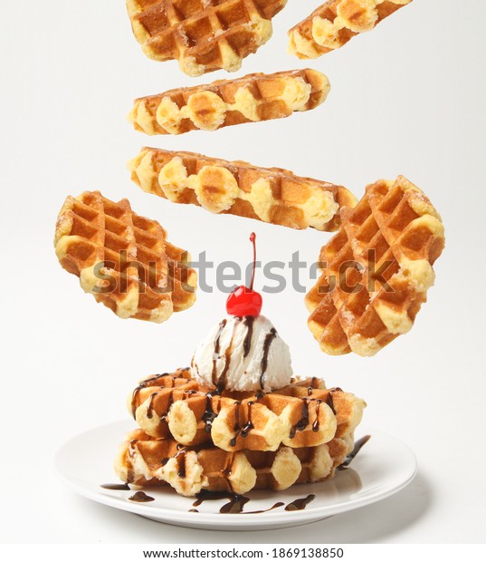 Belgian Liege Waffles With Ice\
Cream Ball And Chocolate Sauce, Cherry On Top And Levitation\
Waffles Around Plate Isolated On White Background. Side\
View.